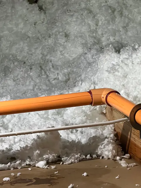 Orange 1.25-inch fire-sprinkler pipe in the attic insulation at the 90-degree elbow