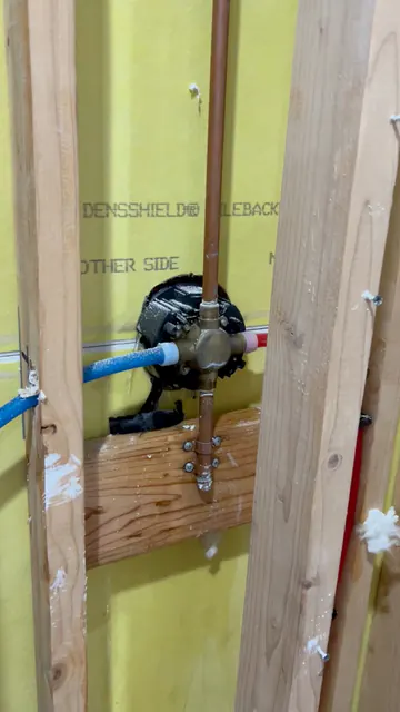 Shower mixing valve exposed in an opened bathroom wall